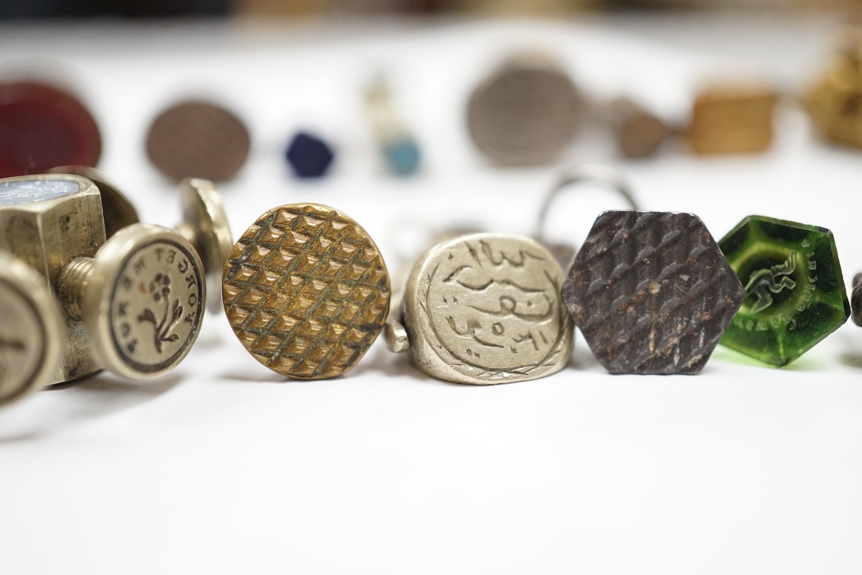 A group of twenty-five steel, gilt metal or nickel fob or desk seals, mostly 19th-century, including a steel swivel seal, a seal with boxwood finial modelled as a hand holding a ball and a nickel multi seal